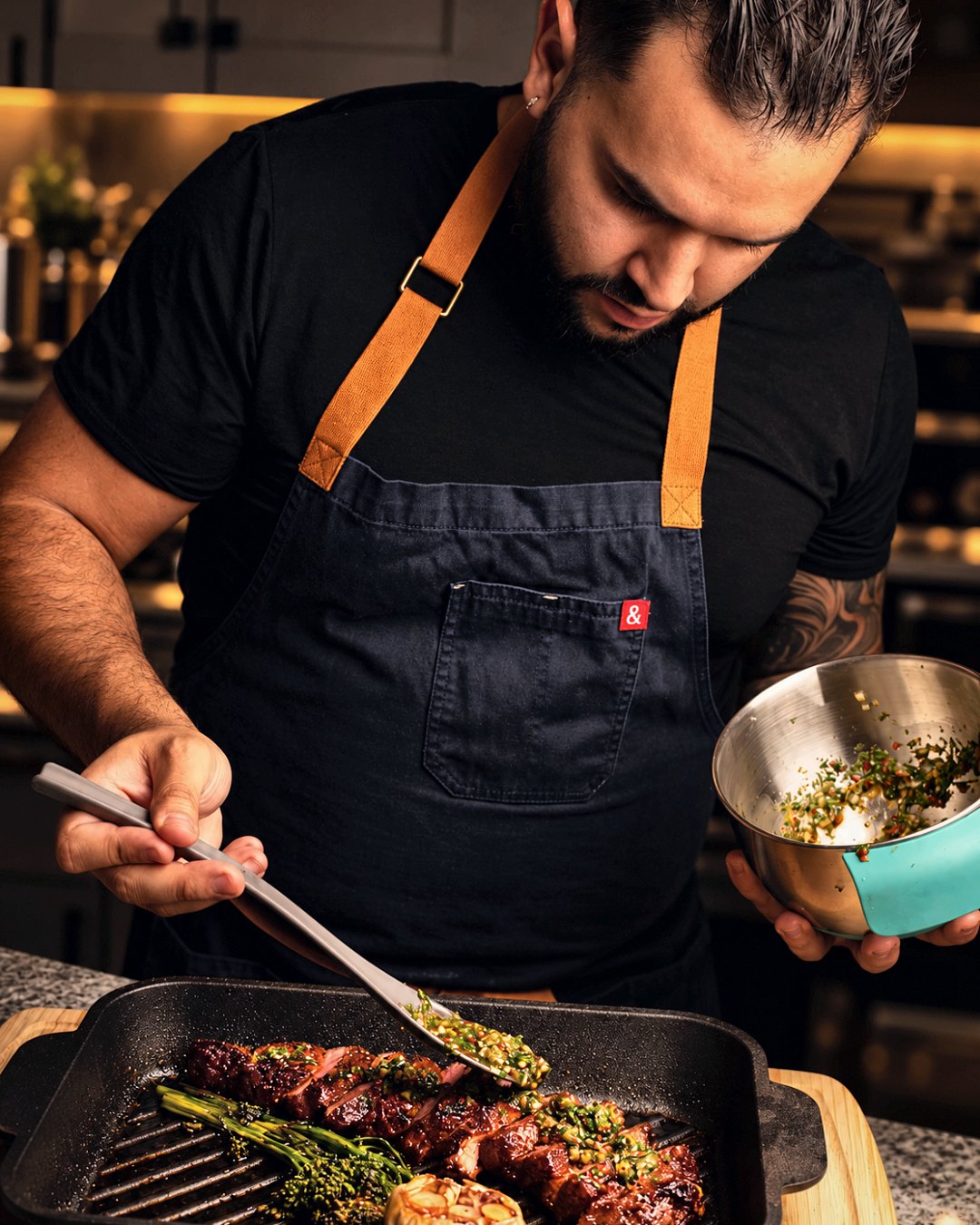 Chef Martin Fassi spooning chimichurri over grilled beef in his kitchen